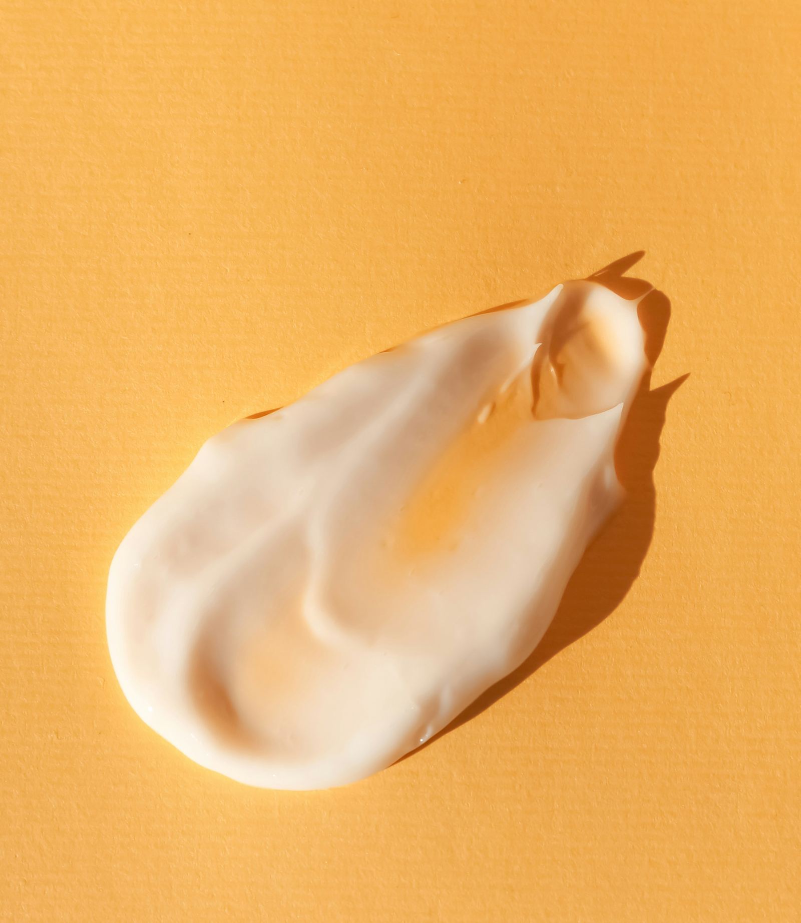 A swirl of pale cream on a warm orange textured surface.